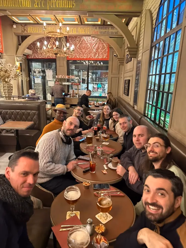 Une douzaine de membres du collectif attablés dans une brasserie, verres en main, souriant à l'objectif